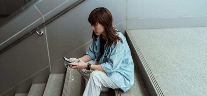 Lady using smartphone while sitting on stairs