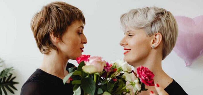 Women Facing Each Other Holding Flowers