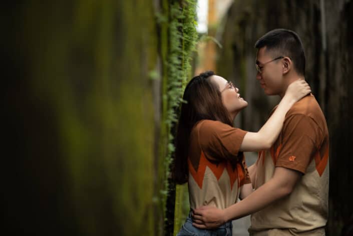 Loving couple embracing near wall with moss