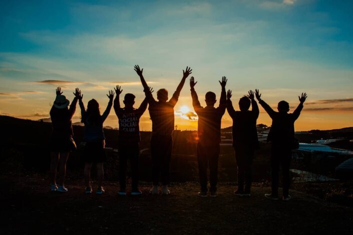 People Raising Their Arms During Sunset