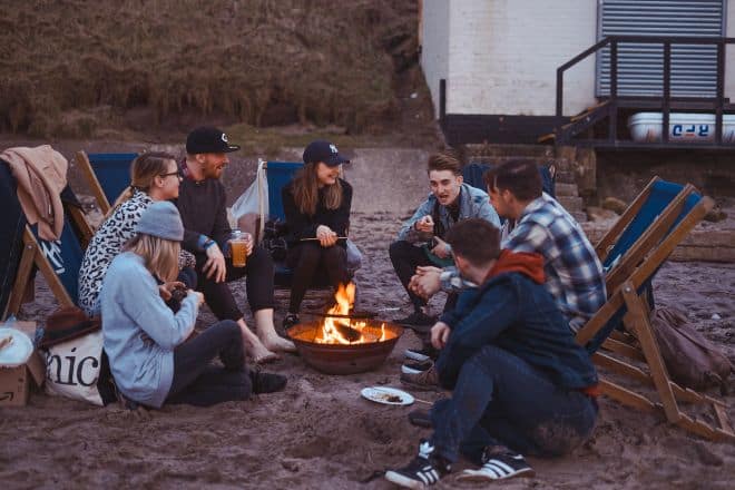 group of people sitting on front firepit - Random Questions to Ask Friends
