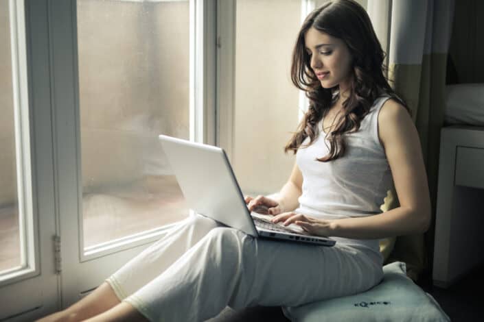 Woman using her laptop by the window