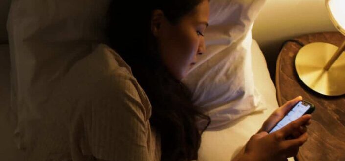 woman using her smartphone while in bed