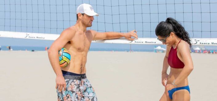 Man and woman talking while playing beach volleyball