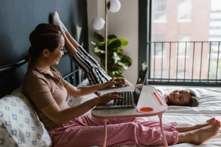 Woman With a Child on Bed While Using a Laptop