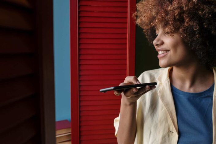 Curly Haired Woman Looking Outside the Window While on the Phone