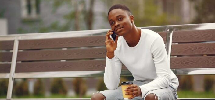 Young Man Using His Phone While Sitting on a Park Bench