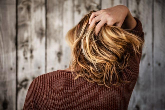 Woman facing the wall holding her hair - DIY Haircut