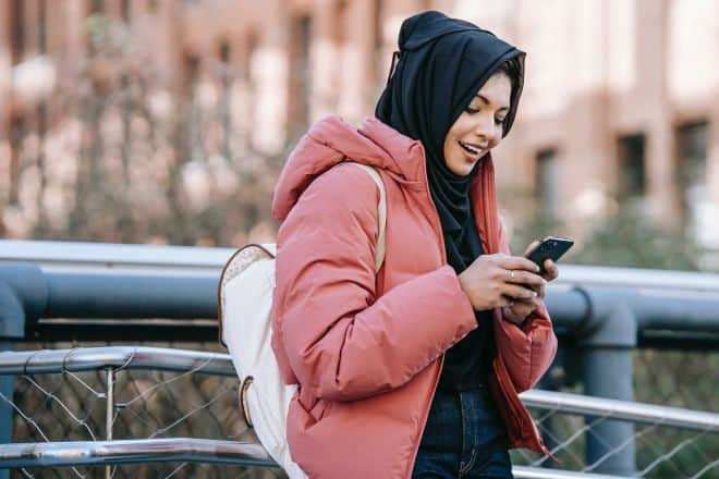 woman in hijab checking smartphone - Good Conversation Topics For Texting