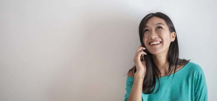Smiling Woman in a Teal Top Talking on the Phone