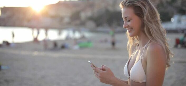 Woman in white swimsuit holding smartphone