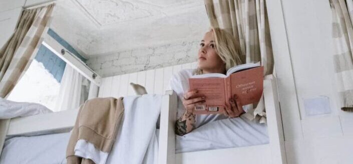 Woman Lying on Top of a Bunk Bed Reading a Book