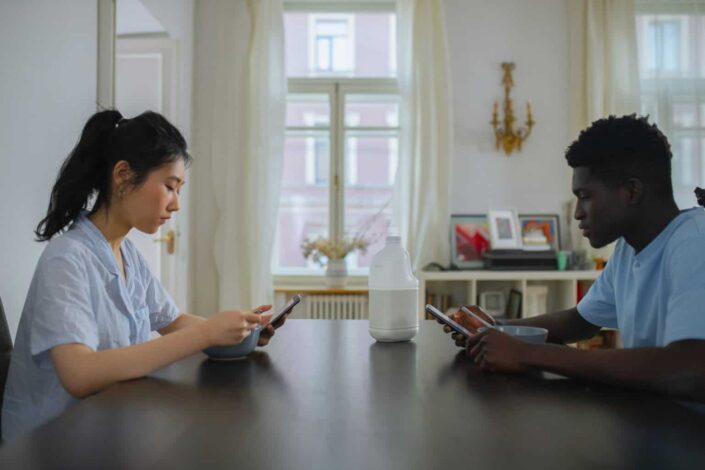 Man and woman sitting at table texting