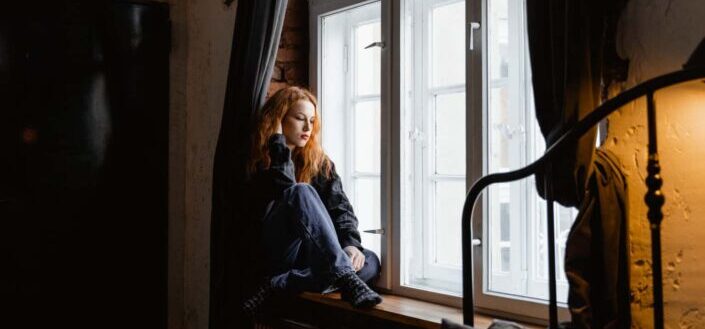 Sad woman sitting by the window