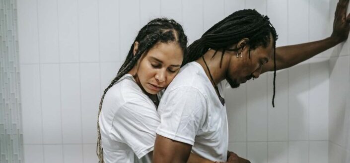 woman hugging stressed husband in bathroom