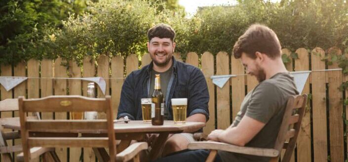 Cheerful men chatting on backyard drinking beer