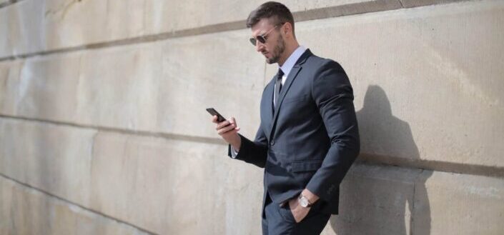Man standing by the wall using phone