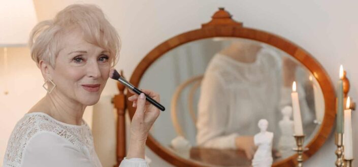 elderly person putting makeup on her cheek