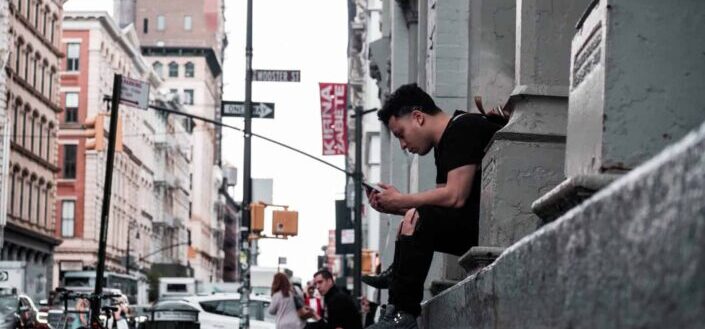Man sitting on pavement looking at phone