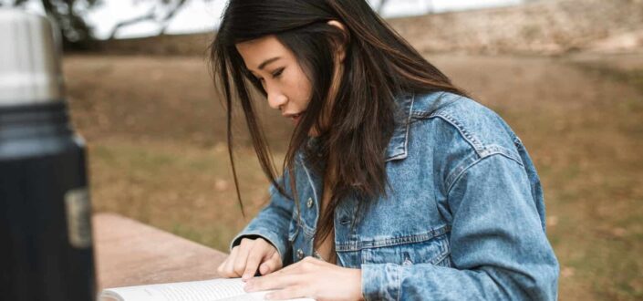 Woman in denim jacket reading a book
