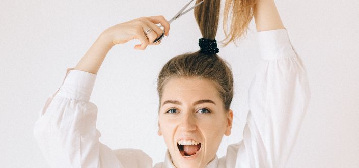 woman trimming her ponytailed hair