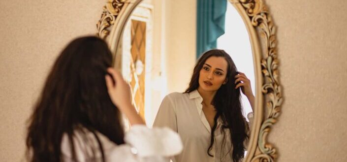 Woman wearing white shirt looking at the mirror