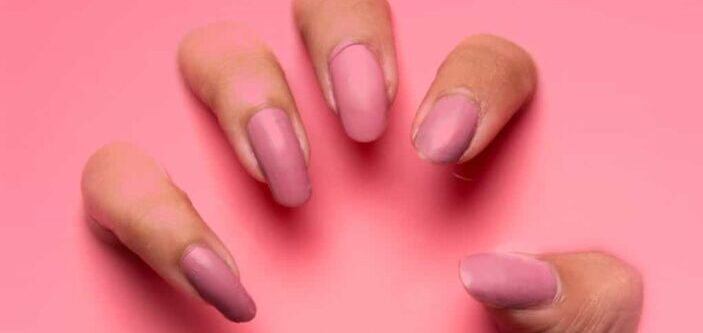 Person with pink manicure on pink liquid